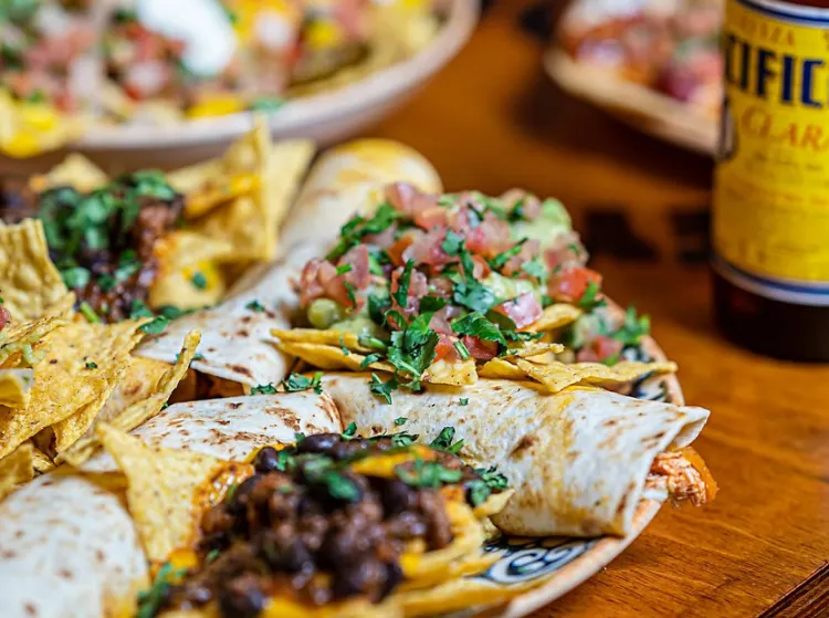 Mesa de El Rey de los Tacos: gringas y nachos con guacamole y pico de gallo, con una cerveza Pacífico